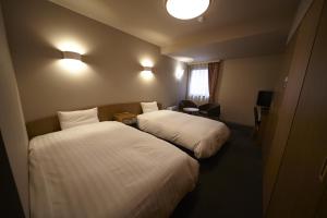 a hotel room with two beds and a window at Dormy Inn Express Sendai Hirose Dori in Sendai
