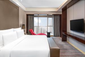 um quarto de hotel com uma cama e uma televisão de ecrã plano em Le Meridien Chongqing Nan'an em Chongqing