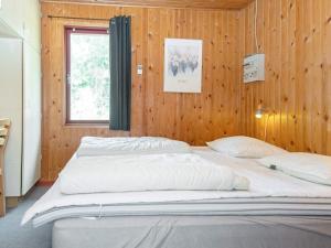 a large bed in a room with a wooden wall at 6 person holiday home in Grenaa-By Traum in Brøndstrup