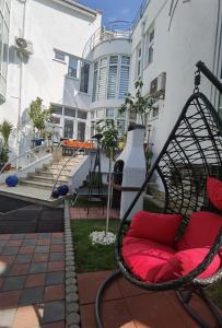 a swing chair in front of a building with red pillows at Fitness House with garden in Constanţa