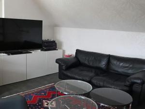 ein Wohnzimmer mit einem schwarzen Ledersofa und 2 Tischen in der Unterkunft Holiday home FALKENBERG XXIX in Falkenberg