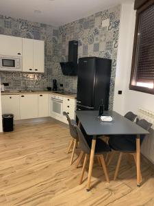 una cucina con tavolo, sedie e frigorifero di Apartamentos el Sabinar a Anchuela del Campo
