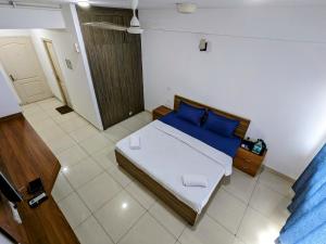 a small bedroom with a bed with blue pillows at PLUTO HOMES in Greater Noida