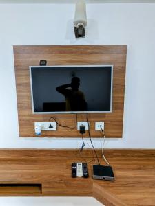 a flat screen tv on a wall with remote controls at PLUTO HOMES in Greater Noida
