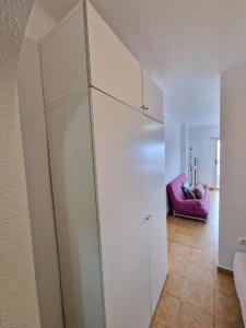 une armoire blanche dans une pièce avec une chaise rose dans l'établissement Apartamento Albatros Beach-6, à Empuriabrava