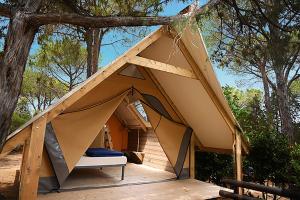 a tent in the woods with a bed in it at Camping Porto Sosàlinos in Cala Liberotto