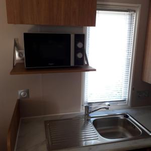 a kitchen with a sink and a microwave at Mobile-home dans camping 4 étoiles in Condrieu