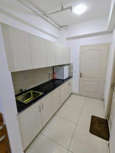 a kitchen with white cabinets and a sink at PLUTO HOMES in Greater Noida