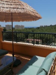 balkon z dużym słomianym parasolem i krzesłami w obiekcie Campoamor Seaview w mieście Campoamor