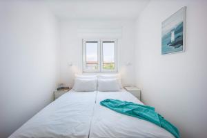 a white bed with a green blanket on top of it at Sea you Soon by the beach, 2-bedrooms suite in Seget Donji in Trogir
