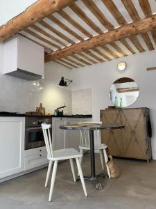 cocina con mesa y sillas en una habitación en La terrasse du pont jullian charme et calme dans le cœur historique, en LʼIsle-sur-la-Sorgue