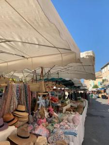 un mercado con sombreros y sombreros expuestos bajo una gran sombrilla en La terrasse du pont jullian charme et calme dans le cœur historique, en LʼIsle-sur-la-Sorgue