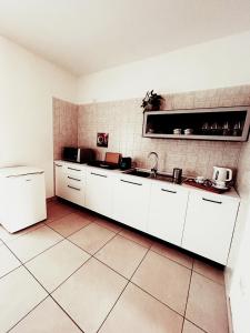 a kitchen with white cabinets and a tile wall at Sunny House Fourteen in Assemini +17 photos
