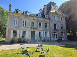 uma casa velha com cadeiras em frente em La Maison Pelloquin em Bernières-sur-Mer