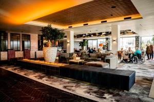 a lobby with couches and people sitting at tables at Van der Valk Hotel Nuland - 's-Hertogenbosch in Nuland