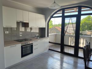 a kitchen with white cabinets and a large window at Apartma pri Cesarjevih in Sežana
