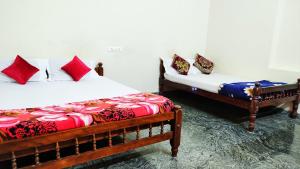 Duas camas num quarto com almofadas vermelhas e azuis em Kurumbalakotta Village Homestay em Padinjarathara