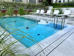 - une piscine avec de l'eau bleue et des chaises blanches dans l'établissement Villa Fedora Luxury Suites, à Lucques