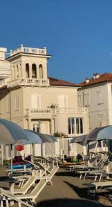 um grupo de cadeiras e guarda-sóis em frente a um edifício em Villa La Torretta Luxury B&B - Adults Only - em Rimini