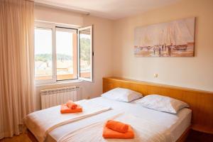 a bedroom with two beds with orange towels on them at Apartmani Miš Rab in Palit