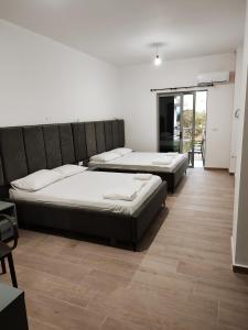 two beds in a room with wooden floors at Petros rooms in Himare