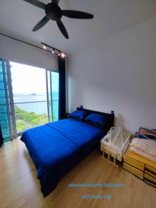een slaapkamer met een blauw bed en een plafondventilator bij Infinite Seaview with Penang Bridge Suite with Sunrise up to 11 person in Bayan Lepas