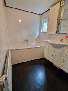 a white bathroom with a tub and a sink at Stacaravan Q10 Marina Beach in Hoek