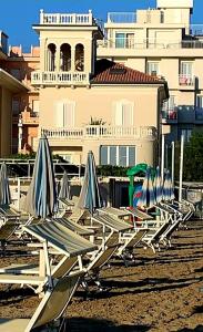 una fila de sillas de césped y sombrillas en una playa en Villa La Torretta Luxury B&B - Adults Only -, en Rímini