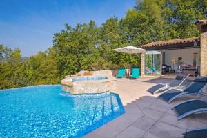 a swimming pool with chairs and an umbrella at Villa Colombes in Draguignan