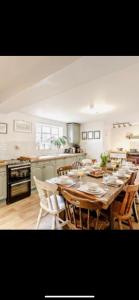 une cuisine avec une grande table et des chaises en bois dans l'établissement Cosy Farm house in Forest of Dean, à Westbury on Severn
