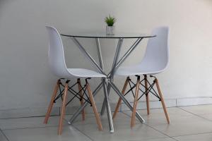 two white chairs and a glass table with a plant on it at Elson Manor Guesthouse in Tzaneen