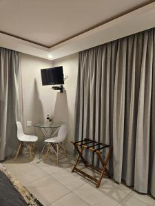 a living room with a television and a table and chairs at Elson Manor Guesthouse in Tzaneen