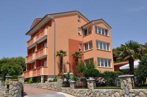 a large orange building with palm trees in front of it at Apartmani Miš Rab in Palit