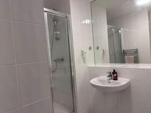 baño blanco con ducha y lavamanos en Modern 2 bed 2 bath Flat Close to Train station en Belvedere