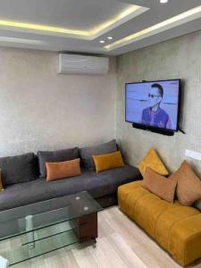 ein Wohnzimmer mit einem Sofa und einem Flachbild-TV in der Unterkunft La location de la mer in Dar Bouazza