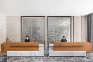 dos personas en una recepción en un vestíbulo en Fairfield by Marriott Zhuhai Xiangzhou, en Zhuhai