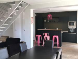 cocina con taburetes rosas y encimera negra en Maison familiale au cœur du Lot en Lanzac