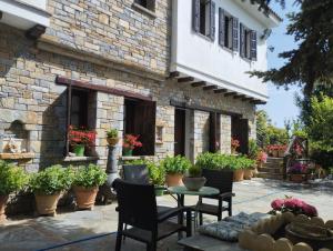 a patio with chairs and a table in front of a building at Dimosthenis Karastamatis Rooms in Xorychti