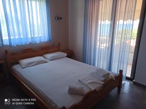 um quarto com uma cama com lençóis brancos e almofadas em Ραπτη Θεοδωρα em Paralia Vrachou
