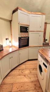 a kitchen with white cabinets and a washer and dryer at Treehouse in Devon - 2 bedrooms in Beaworthy