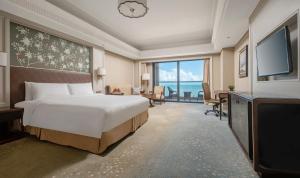 una habitación de hotel con una cama y un televisor en Grand Hotel Haikou - Managed by Accor, en Haikou