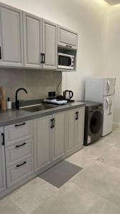 uma cozinha com armários brancos, um lavatório e um frigorífico em dana hotel apartments em Taif