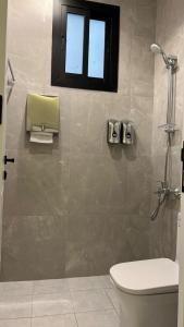 ein Bad mit einer Dusche, einem WC und einem Fenster in der Unterkunft dana hotel apartments in Ta'if