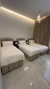dana hotel apartments في الطائف: سريرين في غرفة الفندق ذات شراشف بيضاء