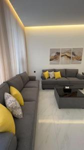 a living room with a gray couch and yellow pillows at dana hotel apartments in Taif