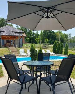 a table and chairs with an umbrella next to a pool at House_Zoi in Čelinac