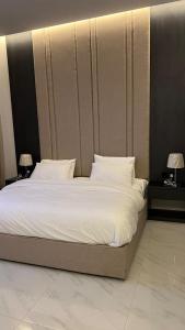 dana hotel apartments في الطائف: غرفة نوم بسرير كبير عليها شراشف ووسائد بيضاء
