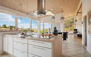une cuisine avec des placards blancs et un grand groupe de fenêtres dans l'établissement Gorgeous Home In Sams With Kitchen, à Onsbjerg