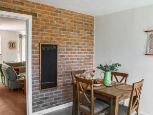 een eetkamer met een bakstenen muur en een houten tafel bij No, 4 Squirrels Nest-uk44305 in Lenwade
