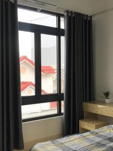 een slaapkamer met een raam met zwarte gordijnen en een bed bij HO GIA AN Home - Căn hộ yên bình in Can Tho
